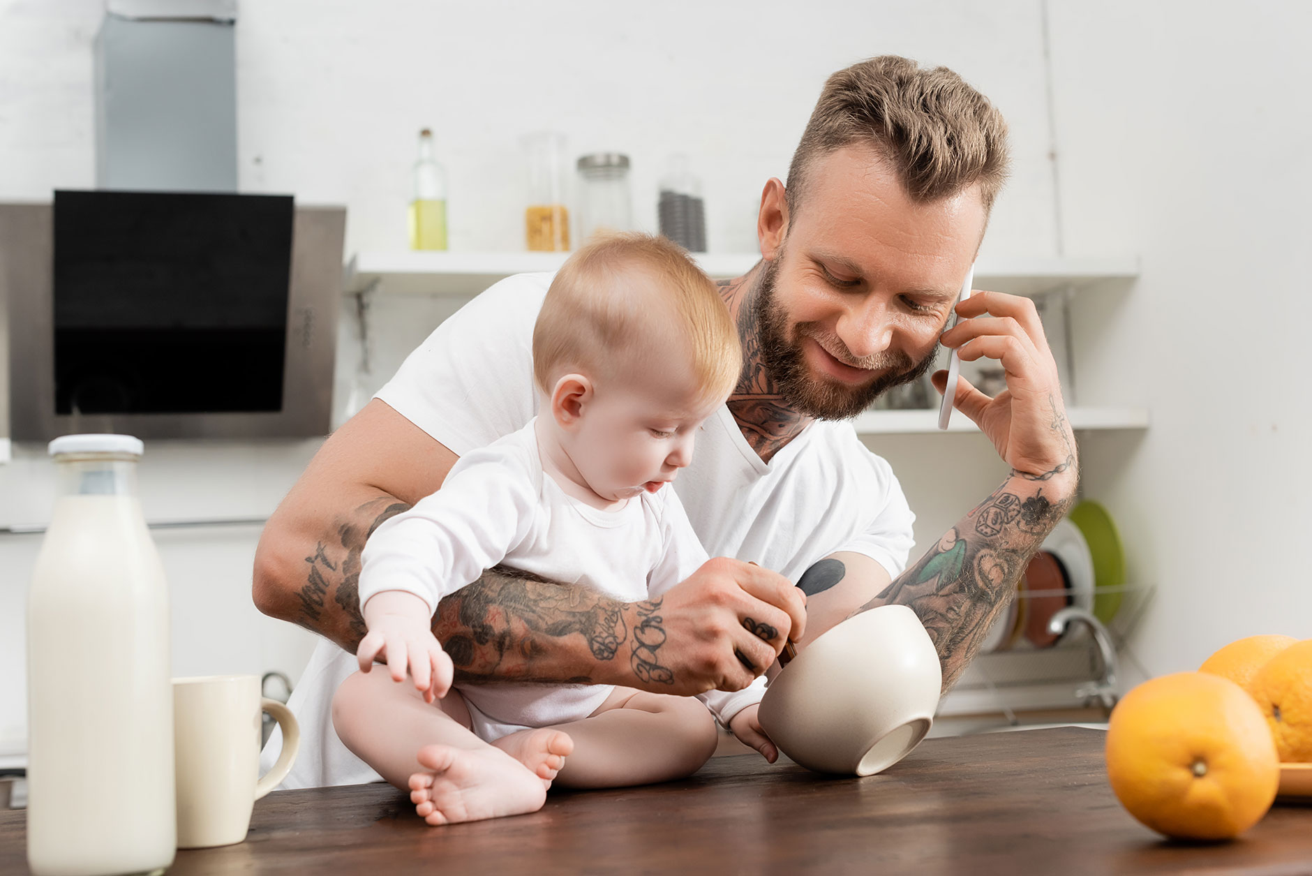 42264002-young-tattooed-man-talking-on-smartphone-near-infant-son.jpg