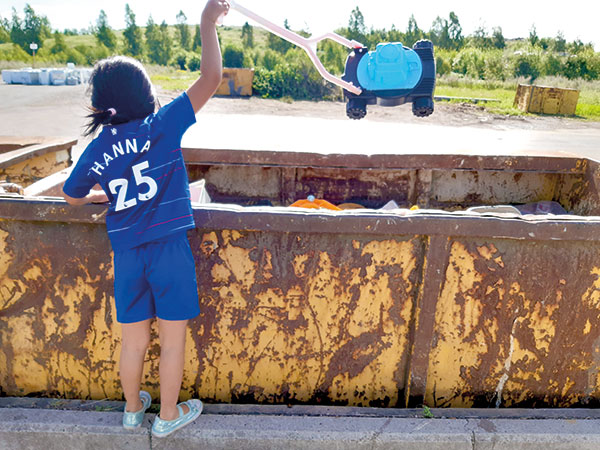 Flicka-i-fotbollskläder-slänger-sin-plastleksak-på-återvinningsstationen.jpg